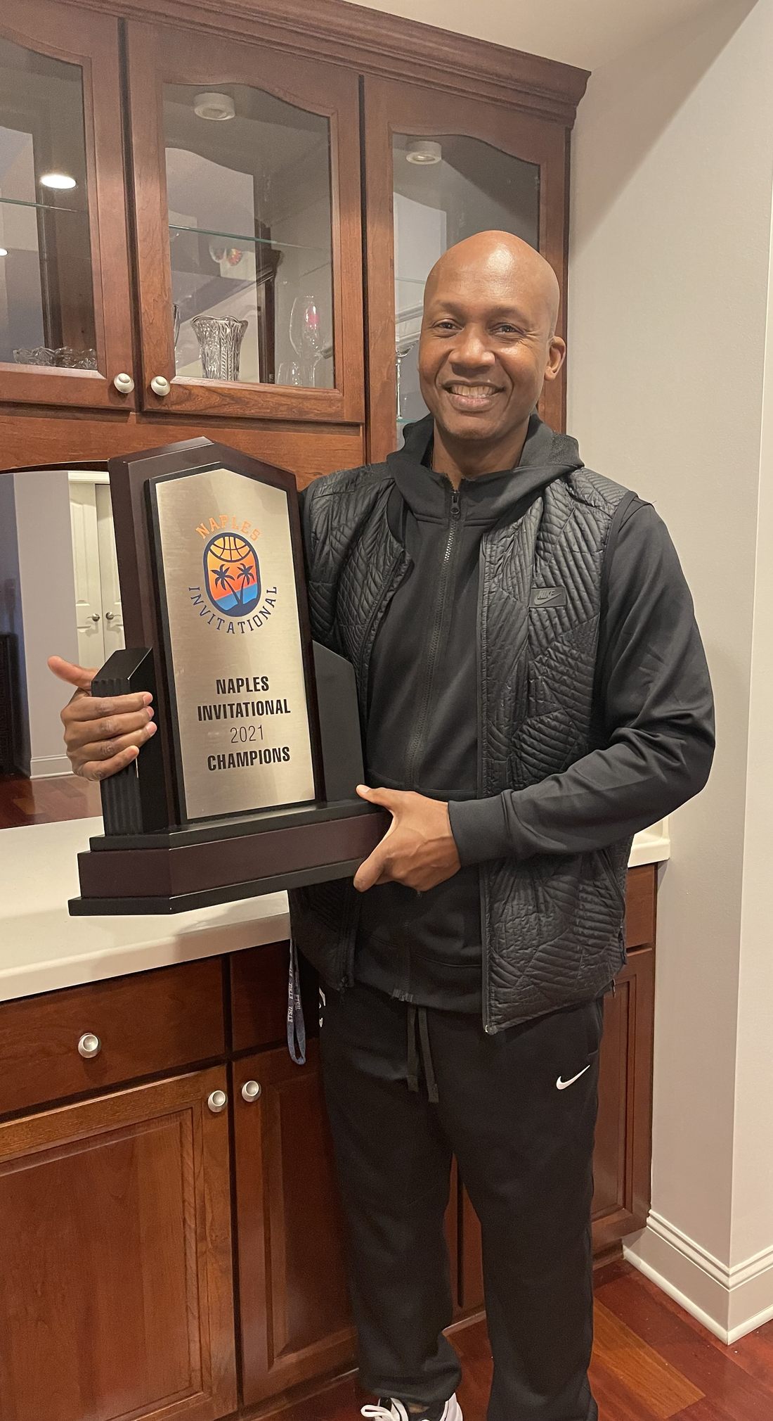 Coach Desmond Oliver holding the 2021 Naples Invitational championship trophy